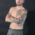 Mann mit Tattoos in olive-grünen Trunks