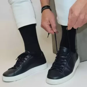 Mann trägt schwarze Socken und bindet seine Schuhe
