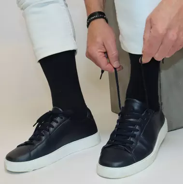 Mann trägt schwarze Socken und bindet seine Schuhe